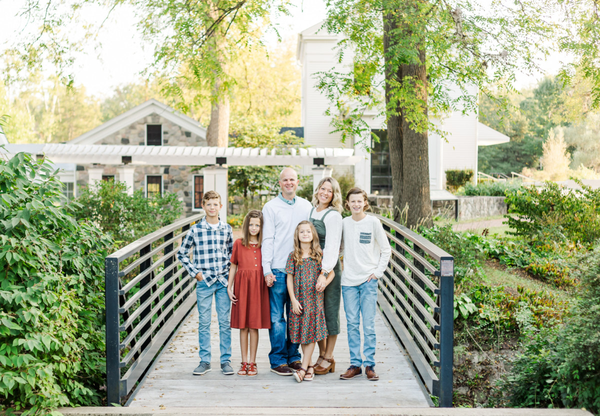 Family is smiling at the camera and standing on a bridge near Ann Arbor Michigan