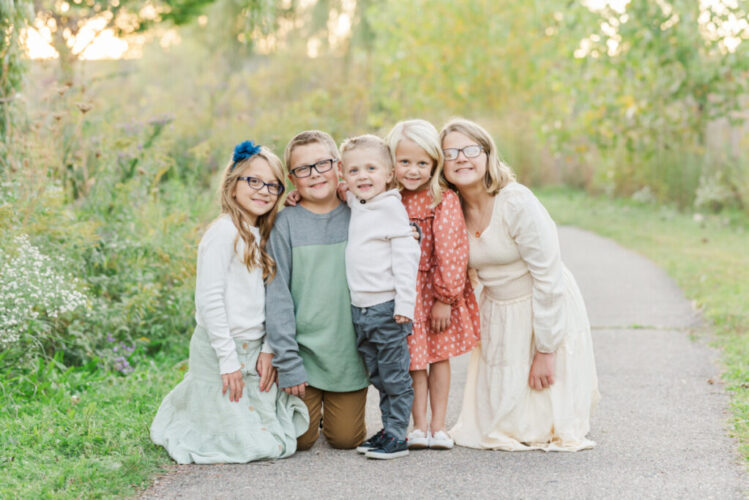 Michigan family photographer shows five children huddled together on a path in a field