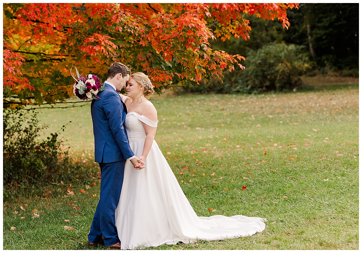 Ann Arbor Wedding Photographer showing a couple standing near a colorful tree forehead to forehead.