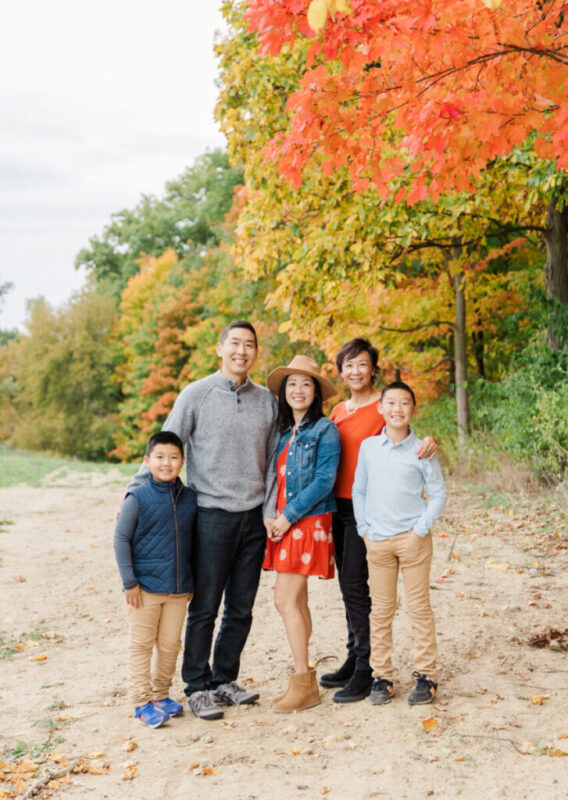 Family session with a family of five standing together on a path smiling at the camera.