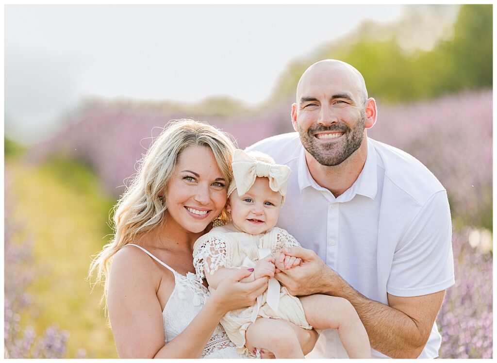 Family smiling at the camera close together while standing in a lavender farm near Ann Arbor Michigan