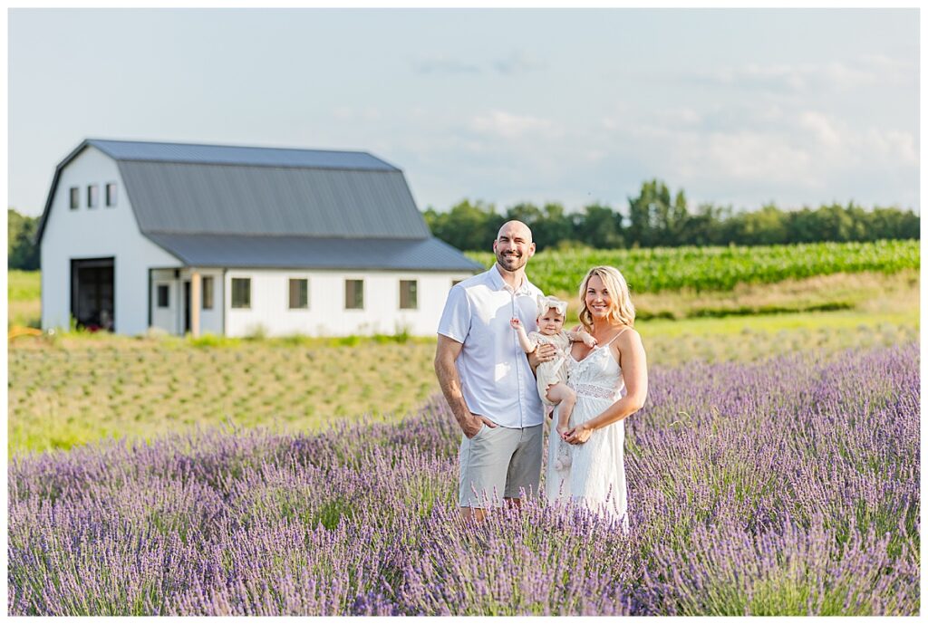 Family standing in a lavender field with a white barn in the background.