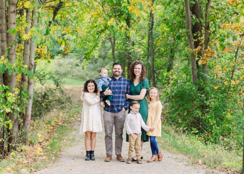 Top 5 Ann Arbor Photo Locations: Family of 6 standing together on a path smiling at the camera at Hudson Mills Metropark. 