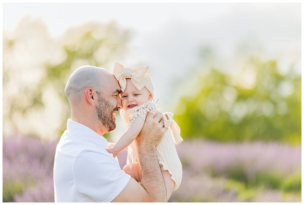 Dad and baby press faces together while standing in a lavender farm at Belle Lavande